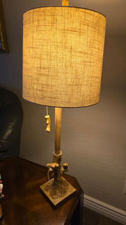 A Rustic table lamp with a tree-branch base and small bird sculptures perched