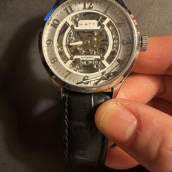 The Maty Black Leather Strap Automatic Watch is a luxurious wristwatch designed for men. Featuring a sleek black case and matching leather band, this 