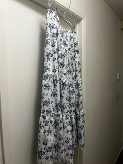 New Flowy tiered maxi skirt has a blue floral print on a white background. It is constructed with an elastic waistband and multiple ruffled tiers. The
