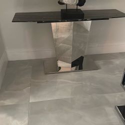 2 console table with a black and white marble top and a polished stainless steel base