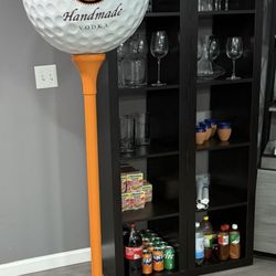 large golf ball on a tee with the Tito's logo and branding
