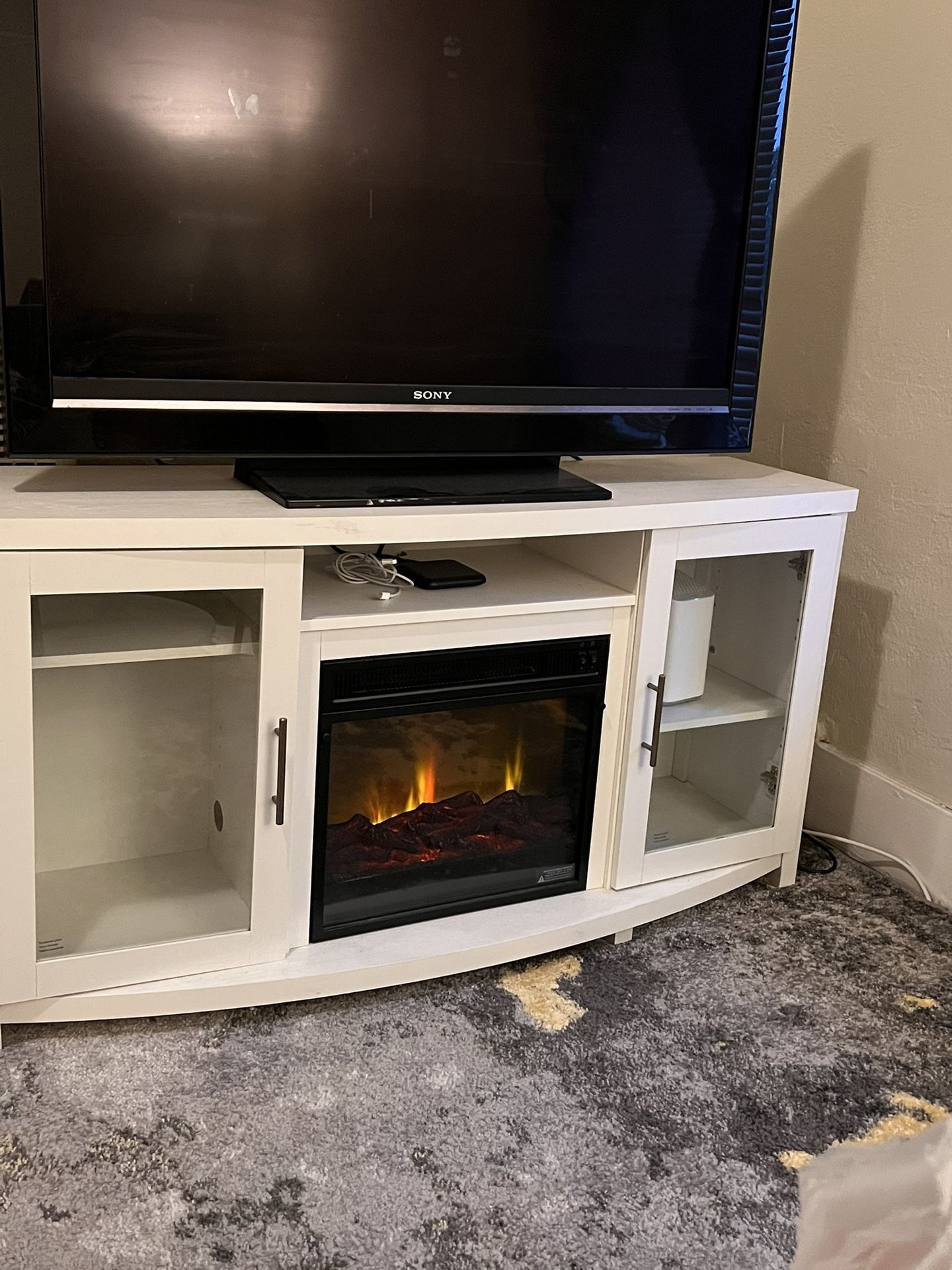 Entertainment Center stand with glass doors and built-in electric fireplace.