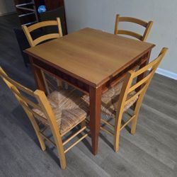 Square wooden dining table with four matching chairs.