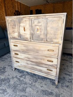 This vintage-style armoire features a whitewashed finish and distinct brass hardware pulls.