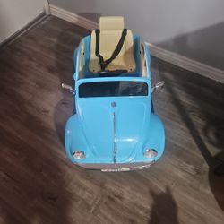 The main item in the image is a blue kids' ride-on car modeled after a vintage Volkswagen Beetle, a battery-powered model. 