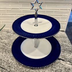  a two-tiered serving tray with white plates with a vibrant blue fluted rim and silver-tone edging