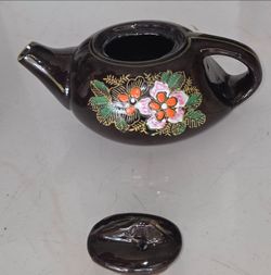 Vintage Japanese black glazed teapot with hand‑painted colorful floral design and gold trim. Lid included. Measures 6"L x 3.5"W. No chips, cracks. Goo