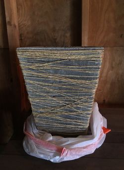 Cement flower planter with twine around it.