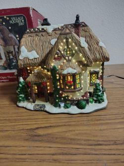 Beautiful Christmas village house featuring a dark green snow-covered roof, large front porch, illuminated windows, and festive holiday details.
Incl