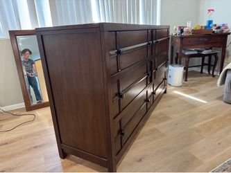 Large dark brown hardwood dresser with decorative mirror.