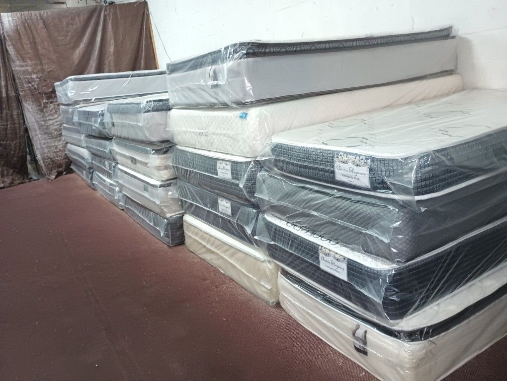 Have All Size Available Good Prices Todos Los tamaños Disponibles Stack of new mattresses wrapped in protective plastic. Multiple styles available.