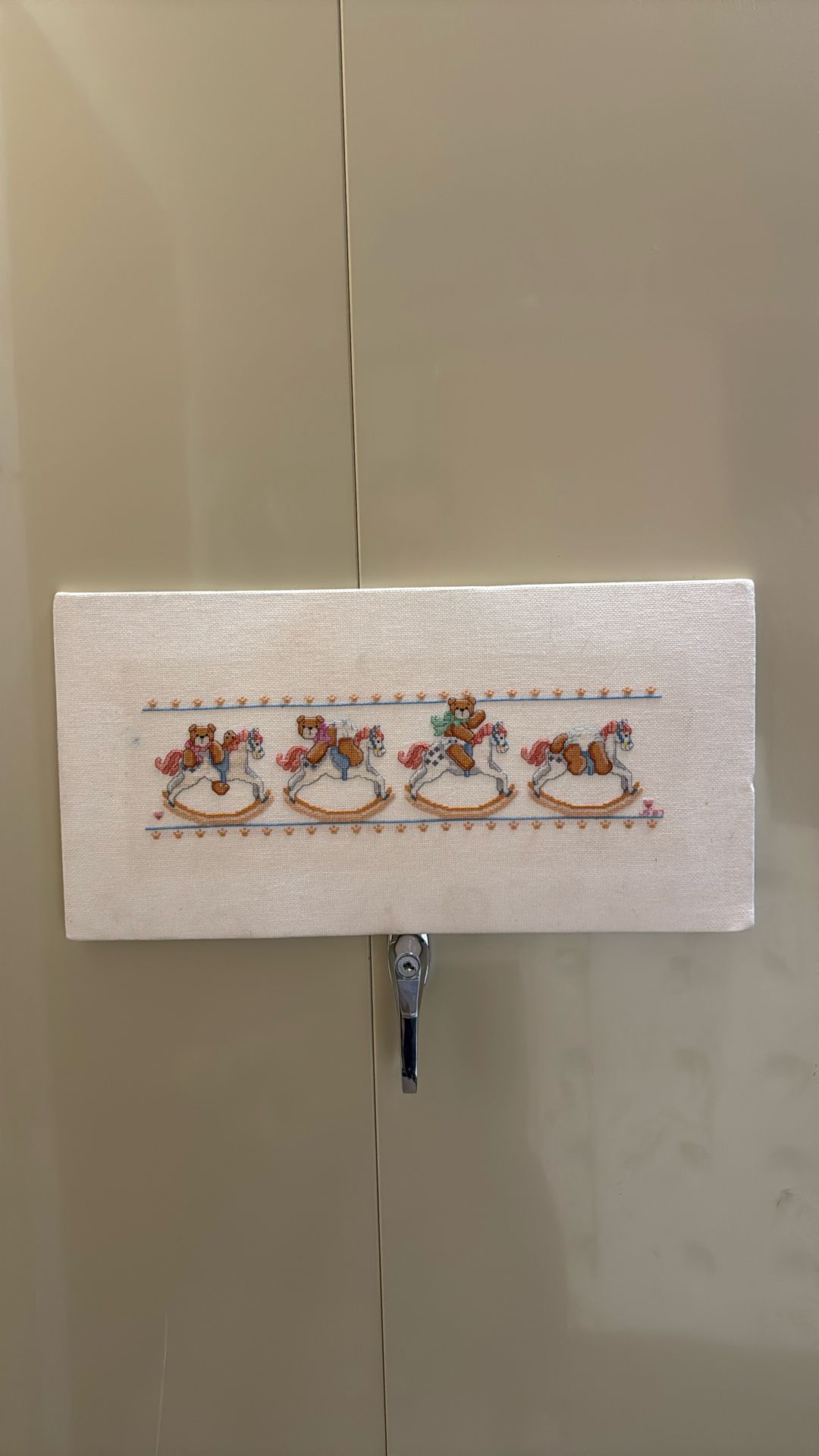 a piece of fabric on canvas with embroidered design featuring four teddy bears riding rocking horses