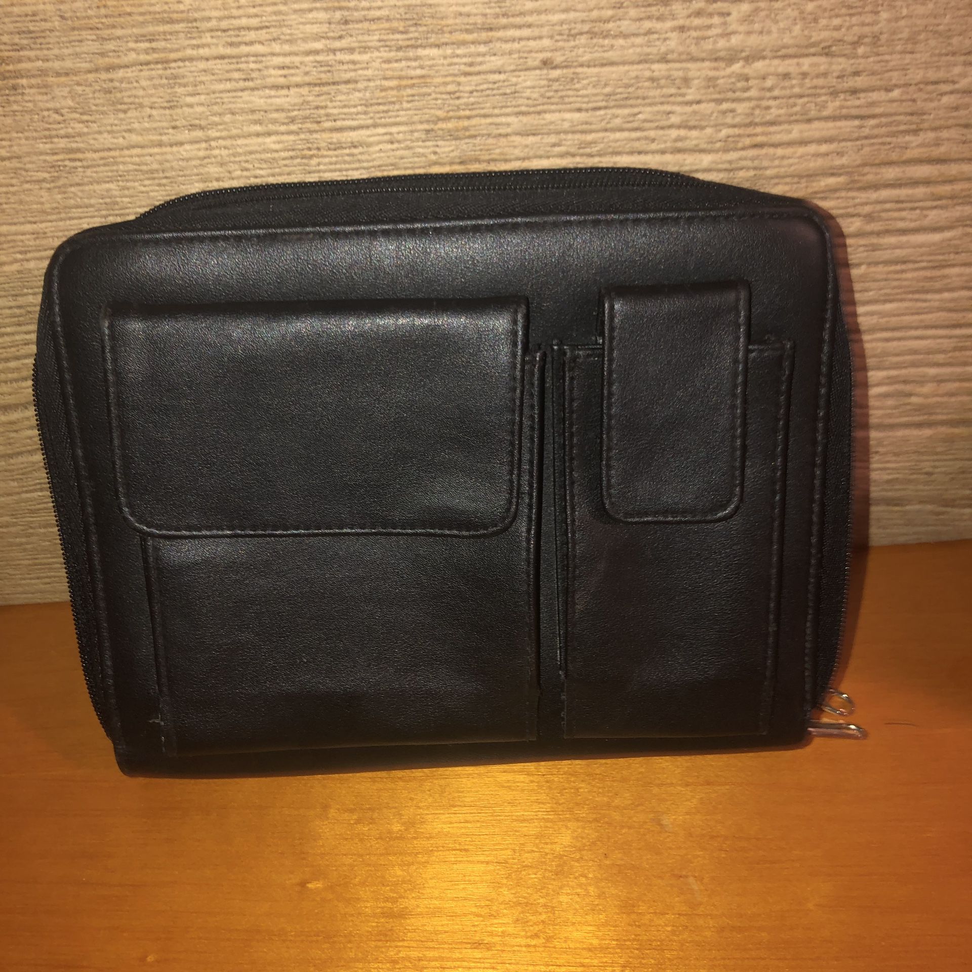 Black leather case/binder/wallet/planner with two zip closures and outside Velcro compartments. There’s a place with 6 rings to put papers or planner