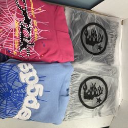 Two Hellstar Yoga Black And Grey Tees And Two Spider Hoodies V2 Pink And Sky Blue With Rhinestones All Larges Except Pink V2 That’s A Medium