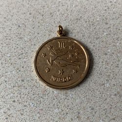 vintage Sarah Coventry zodiac pendant is a gold-tone Virgo sign charm likely from the 1970s. It features a raised maiden figure against a textured bac