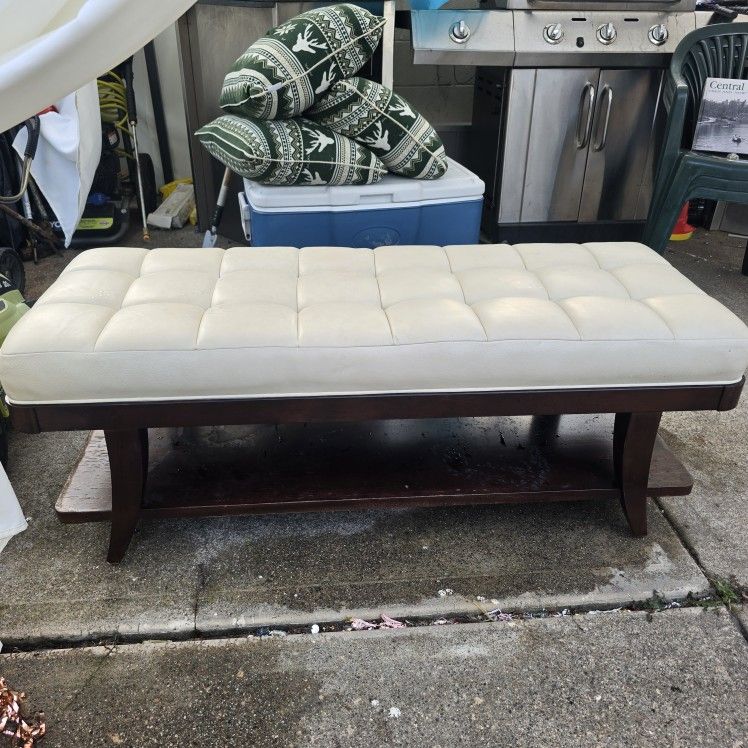 Off-white upholstered bench with a Tuffed Cushion.