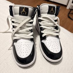 Air Jordan 1 Mid in Black/Gold/White patent leather.