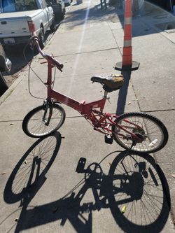 This is a red full-suspension folding bicycle. 