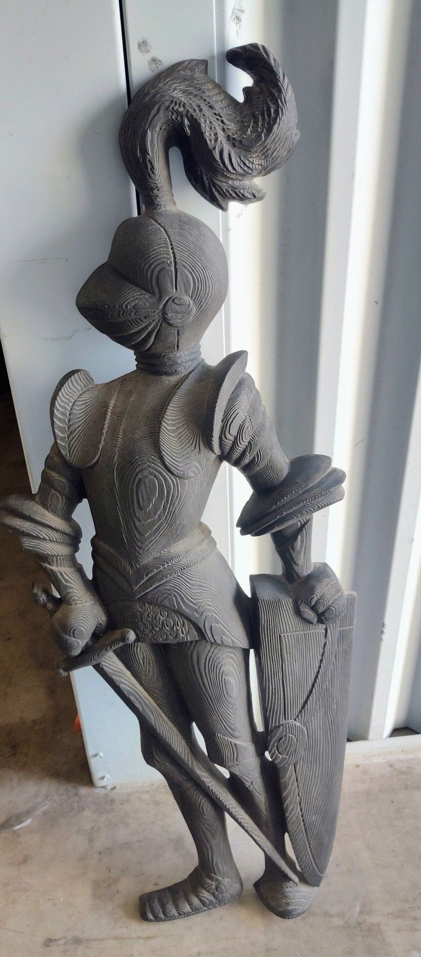 statue of a medieval knight in armor holding a sword and shield. 