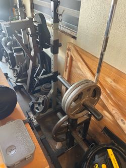 Squat Rack with Barbell, Weight Plates and bench.