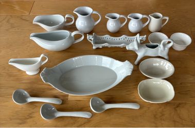 White ceramic serving pitchers, cow creamer, ladles, platters, and bowls. Buy all fir $50.00.