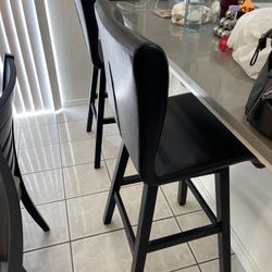 black faux leather upholstered swivel bar height chairs with a solid wood frame