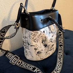 KARL LAGERFELD PARIS  Bucket Bag with bold logo webbing strap and charms. 

