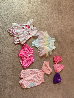 Huge grey bin full of baby clothes and hats.