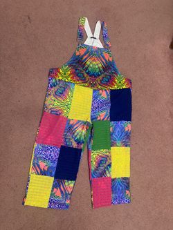 Bold neon patchwork overalls with eclectic printed panels. Adjustable straps and roomy fit for easy movement. Bright, playful look perfect for festiva