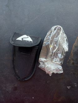 Brand new stainless steel mini folding camping trowel alongside its black nylon carrying pouch lot8