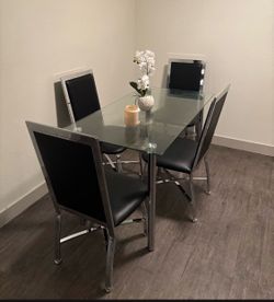 Glass dining table with four chairs.