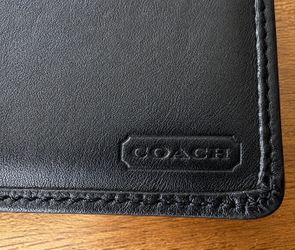 Coach black signature embossed leather bifold wallet.