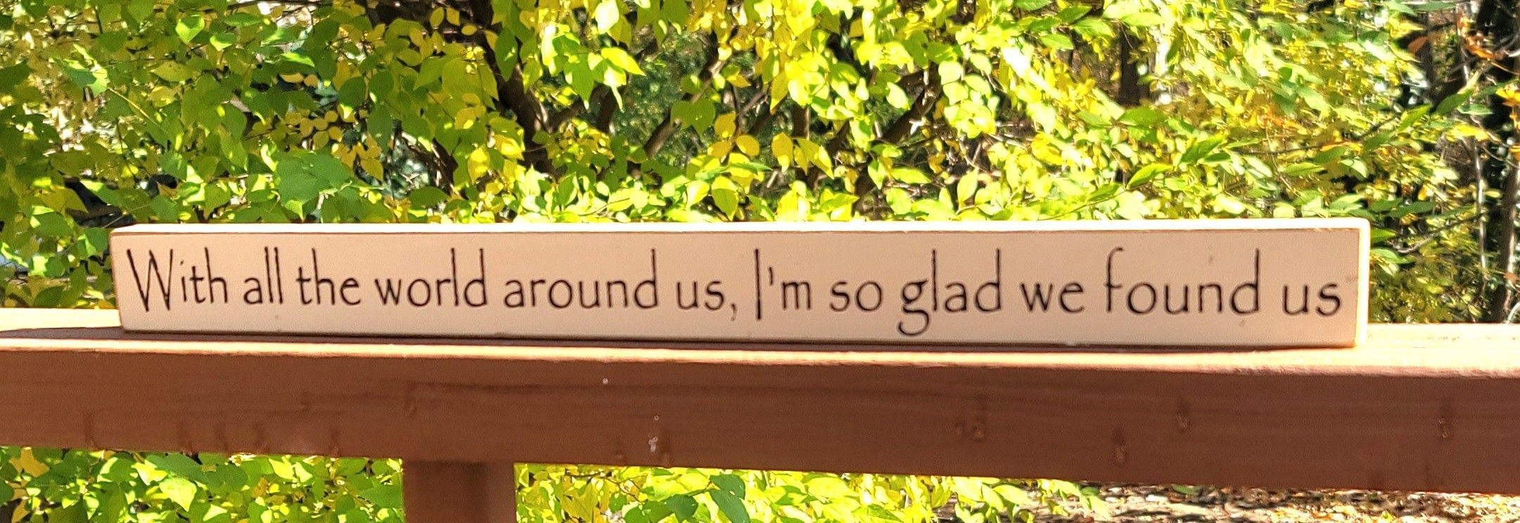 Wooden decorative sign with the text: "With all the world around us, I'm so glad we found us".