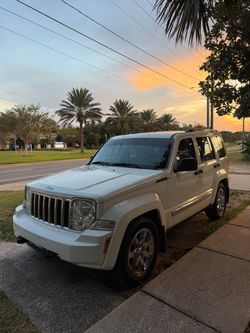 Reliable white Jeep Liberty Limited 4x4 with a 3.7L V6 engine. This SUV has chrome wheels, roof rails, a tow hitch, and tinted windows. The exterior i