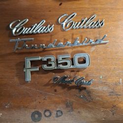 VINTAGE AUTO EMBLEMS,  THUNDERBIRD,  CUTLASS, MONTE, F350, AND FAIRLANE 500. ALL IN GOOD CONDITION,  NEEDS CLEANING
