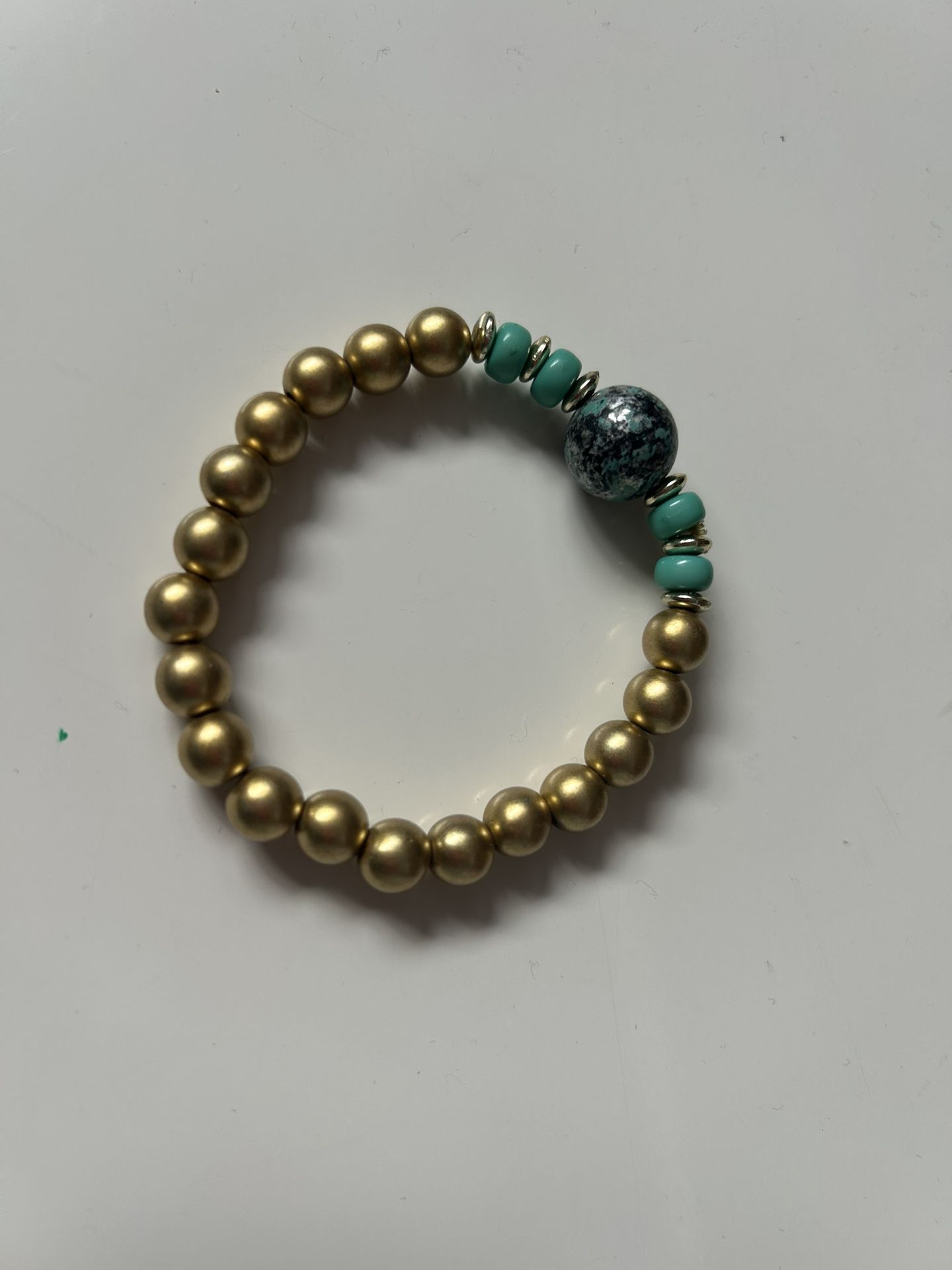 gold-toned beaded stretch bracelet featuring turquoise-colored and dark mottled beads