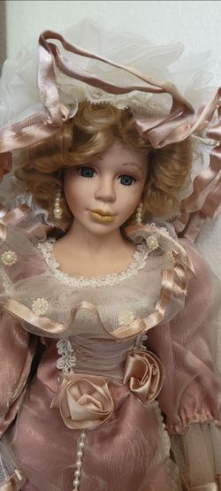Porcelain doll wearing a pink, tiered Victorian-style gown