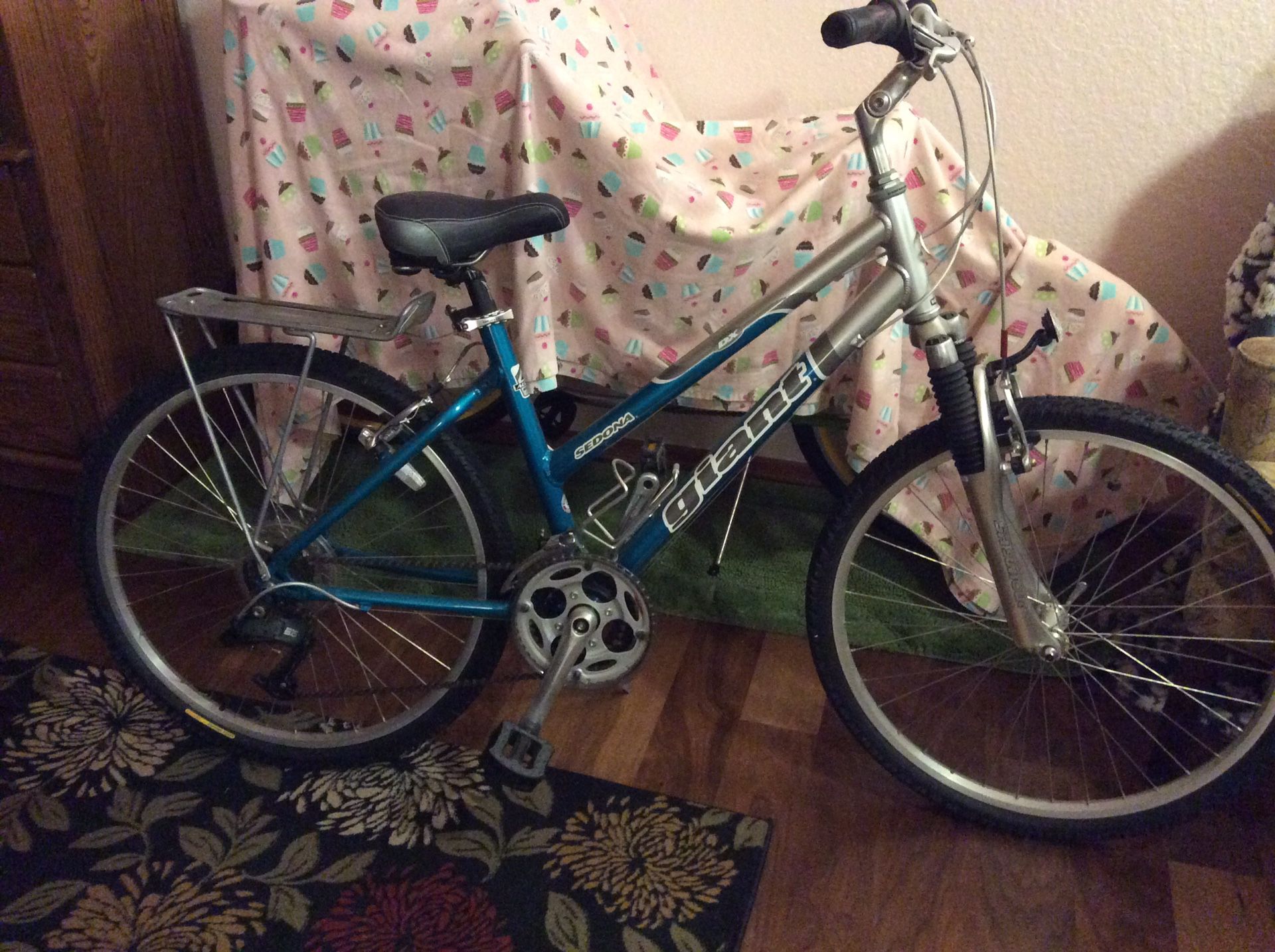 Woman’s beautiful teal and silver Giant Sedona bike. A rack over the back tire for carrying items.....water bottle rack fits most containers. Tires
