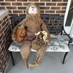 Autumn decor - sitting straw man holding pumpkin and dried flowers