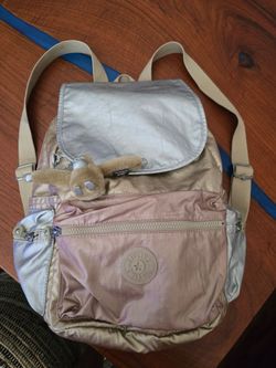Stylish backpack in a metallic beige-gold, rosegold, silver, finish. Lightweight design with multiple exterior pockets for easy organization. Adjustab