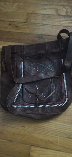 Handcrafted dark brown leather crossbody bag with intricate hand-tooled patterns and colorful embroidery. This bag has a front flap pocket with a tie 