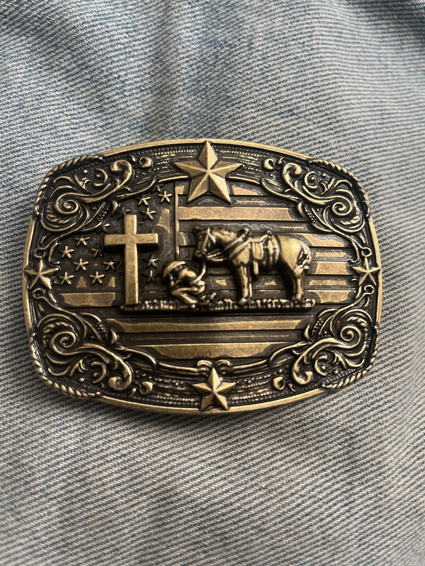 new gold patina western belt buckle featuring a cross and horse flag on the background