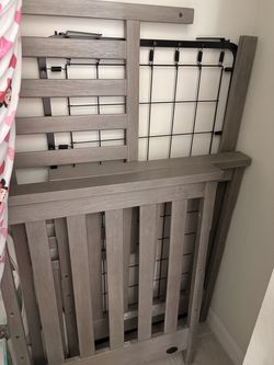 Gray Wooden Crib Frame  Sturdy gray wooden crib frame with metal support.