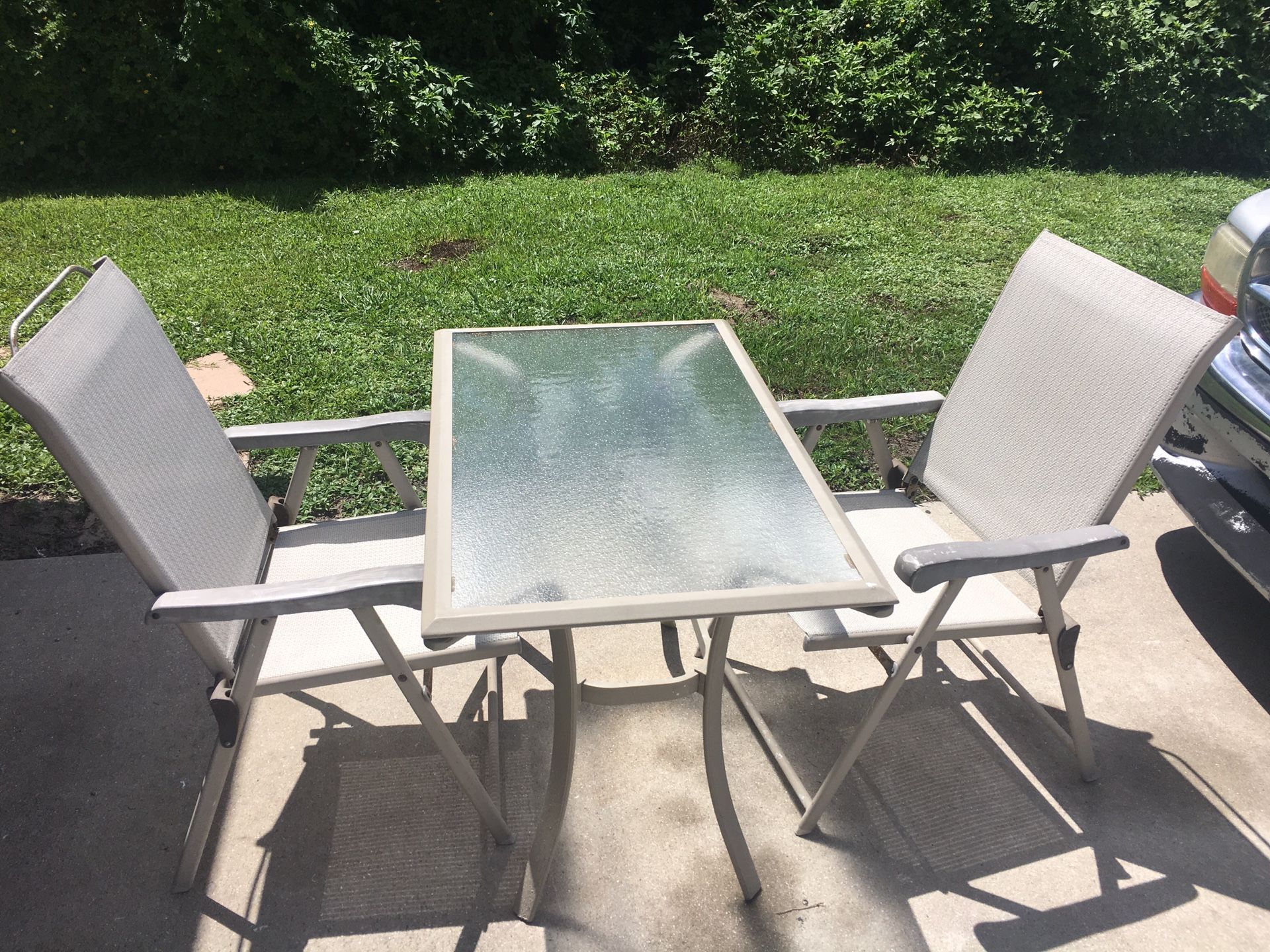 patio furniture glass table and two folding chairs