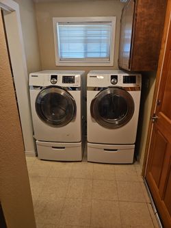 Samsung washer and electric dryer with pedestals.