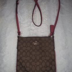 Coach F58309 Signature North South Crossbody bag in brown coated canvas with pink or fuchsia leather trim and strap.