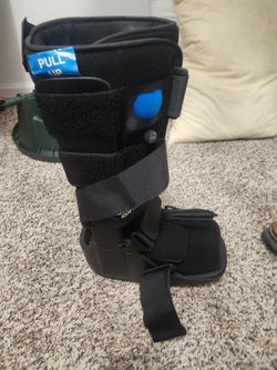 black United Ortho Air Cam Walker Fracture Boot featuring a soft inner liner with a blue "PULL UP" tab, adjustable hook-and-loop velcro straps, and an