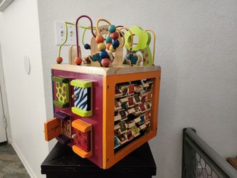 Colorful wooden activity cube with various interactive elements and been for baby to ride