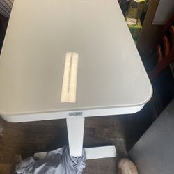 This is a Seville Classics airLIFT adjustable height desk with a white glass top. The desk features a tempered glass surface that me