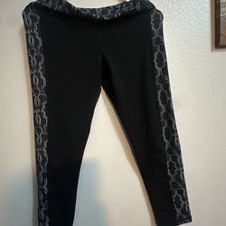 The leggings feature a deep black base with a distinctive silver metallic geometric trellis pattern running down the outer sides of each leg and acros